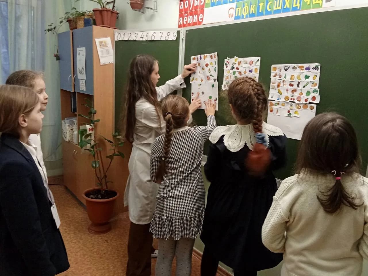 Школьницы в классе прикрепляют к доске карточки с полезными продуктами